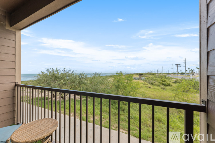 A balcony with a table and chairs overlooking a grassy area.