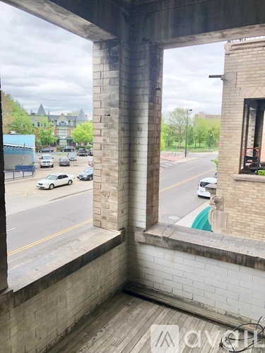 A view from a window looking out at a street with cars and buildings.