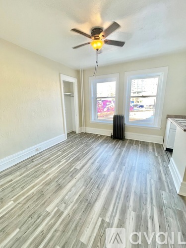 A room with a ceiling fan and wood flooring.