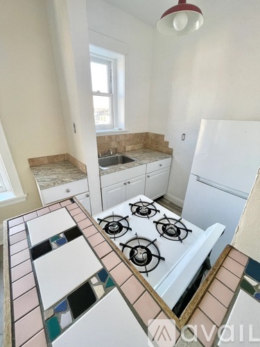 A kitchen with a white stove top and a tiled counter.