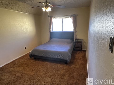 A bedroom with a bed, carpet, and a ceiling fan.