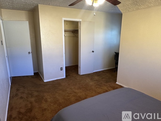 A room with a carpeted floor and a ceiling fan.
