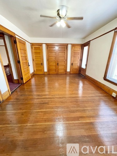 A spacious room with wooden floors and a ceiling fan.