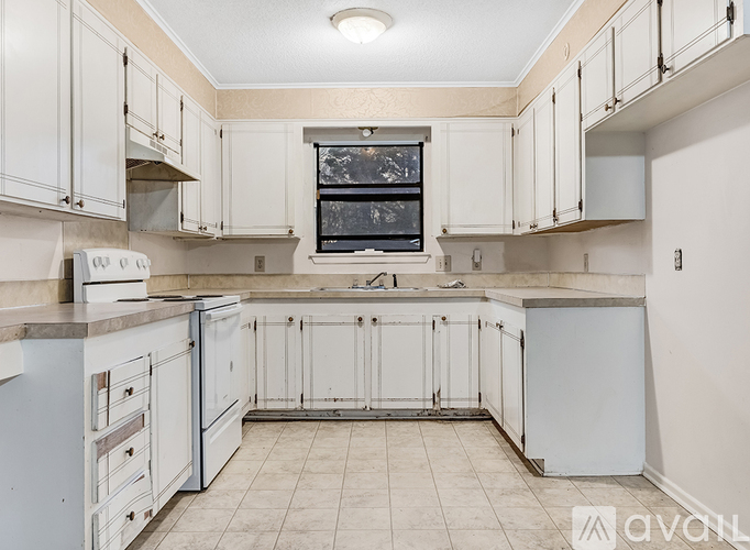 A kitchen with white cabinets and a window above the sink.