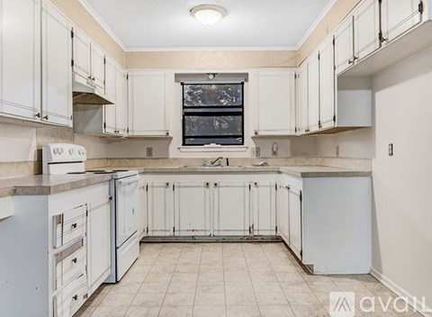 A kitchen with white cabinets and a window above the sink.