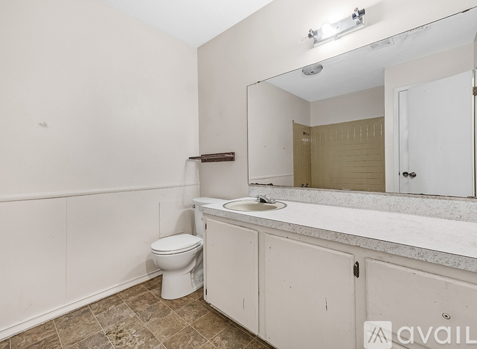 A bathroom with a toilet, sink, and mirror.