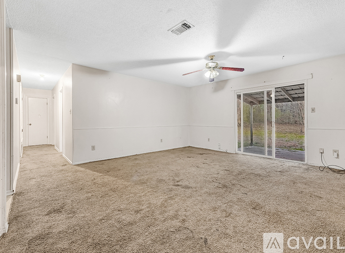 A spacious room with a ceiling fan and carpeted floor.