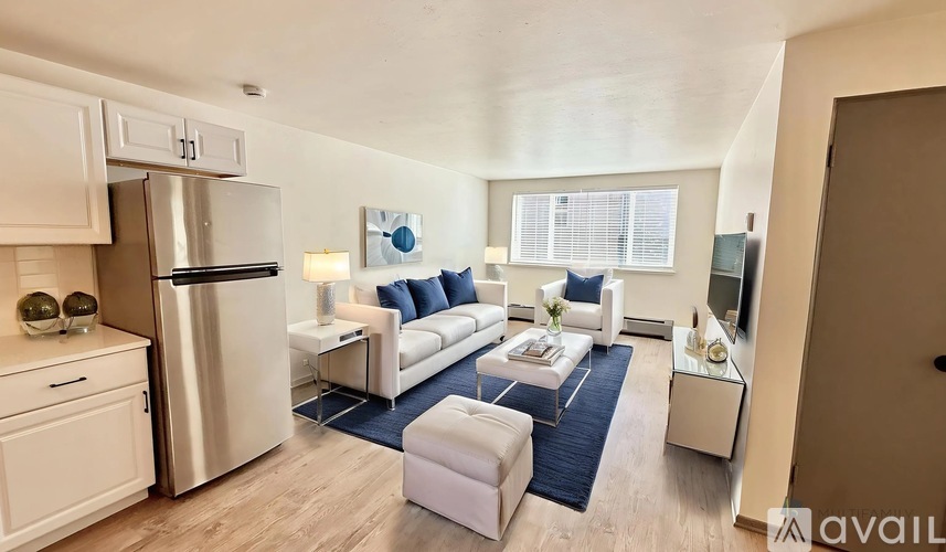 A modern kitchen with a refrigerator, stove, and a dining area with a couch and chairs.