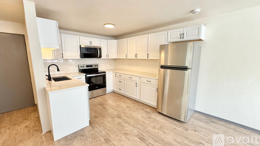 A kitchen with white cabinets and a wooden floor.