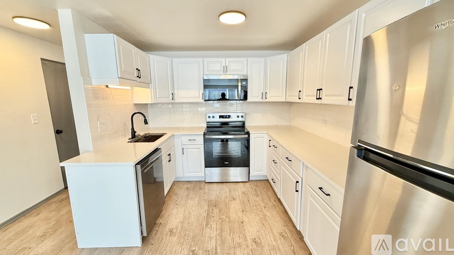 A kitchen with white cabinets and a wooden floor.