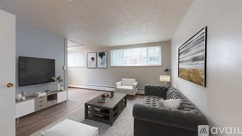 A living room with a black couch, a television, and a painting on the wall.
