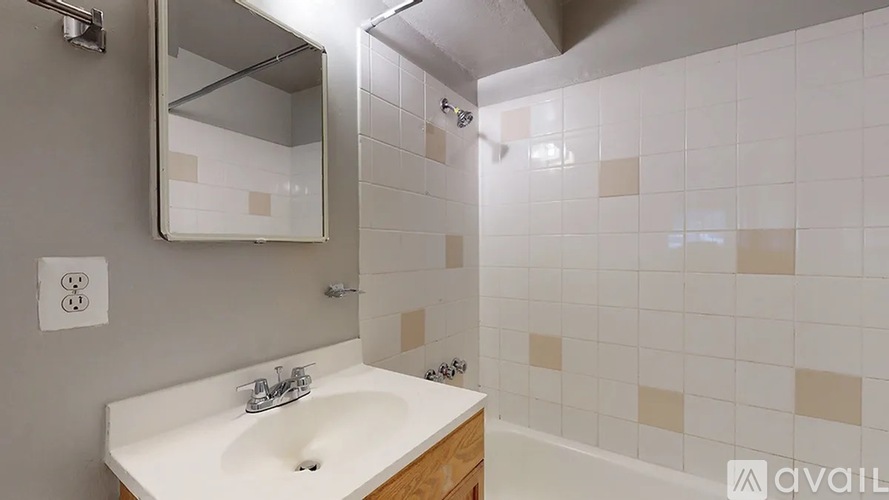 A bathroom with a sink, mirror, and tiled walls.