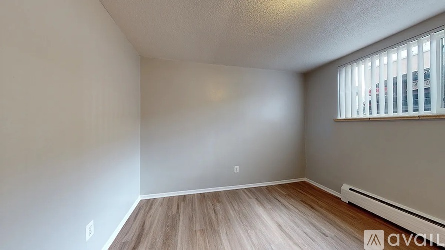 A room with wooden flooring and a window with blinds.