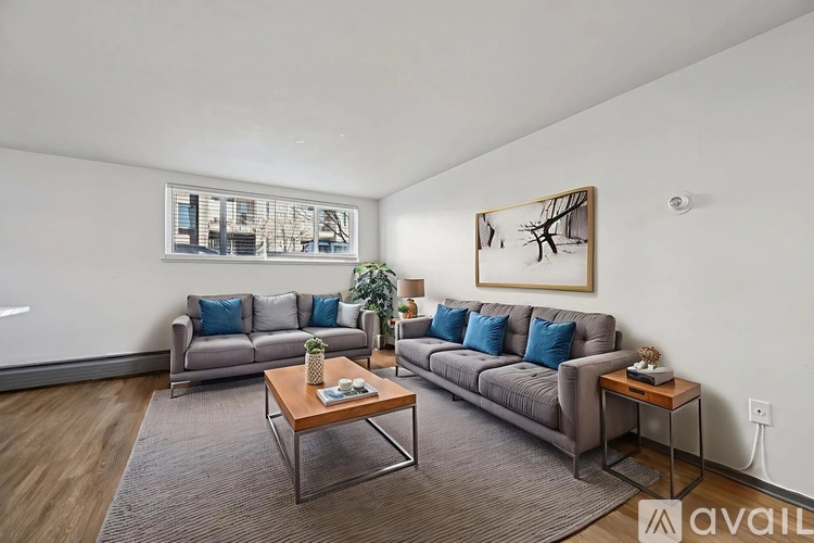 A living room with a grey sofa, a wooden coffee table, and a painting on the wall.
