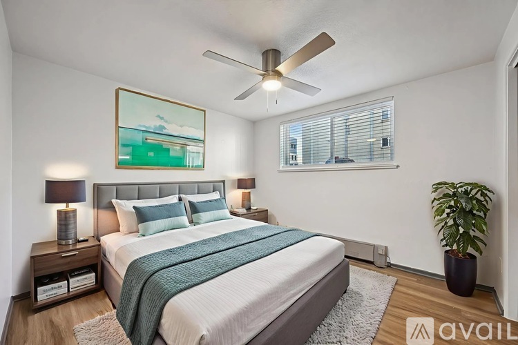 A bedroom with a bed, a ceiling fan, and a painting on the wall.