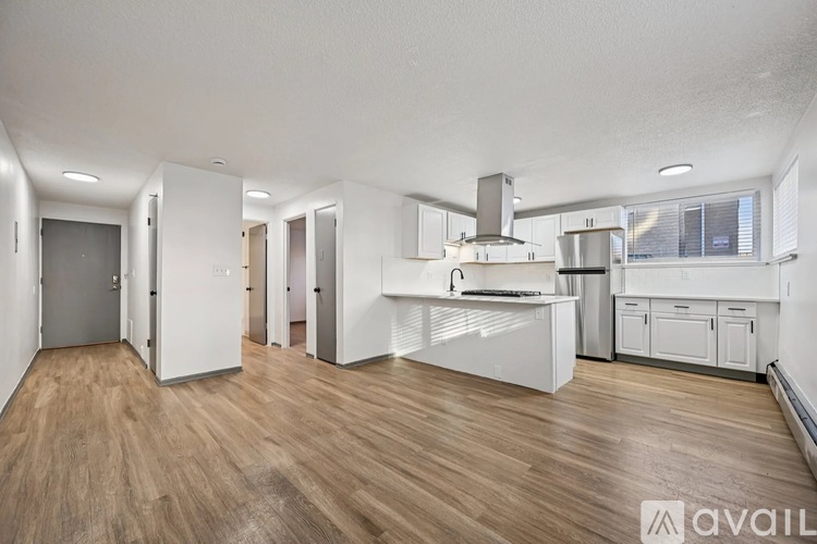 A spacious kitchen with white cabinets and a wooden floor.