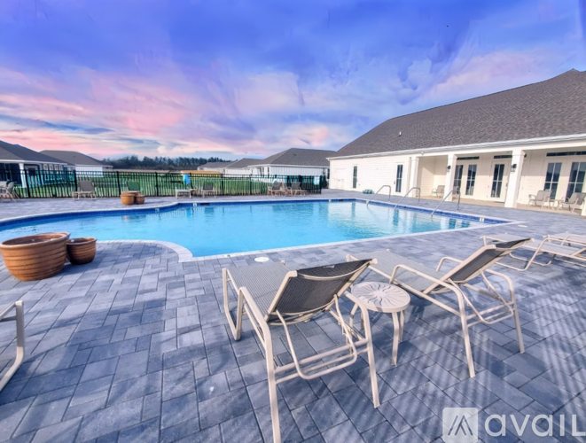 A pool with chairs around it and a house in the background.