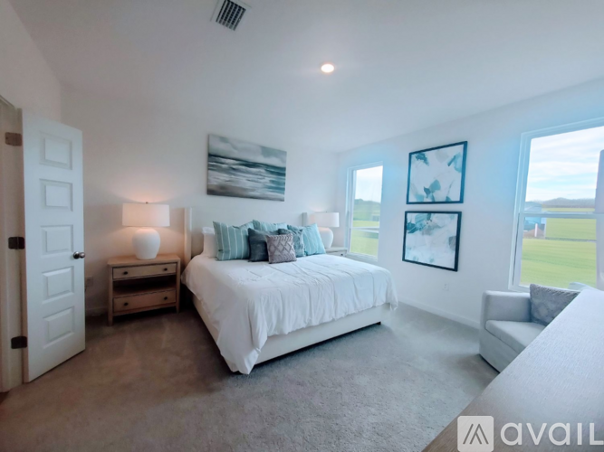 A bedroom with a large bed, a nightstand with a lamp, and a window with a view of the outside.