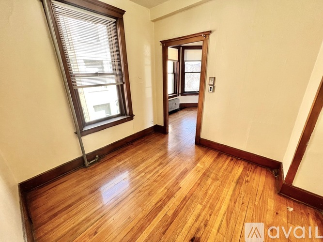 A room with wooden floors and a window with blinds.