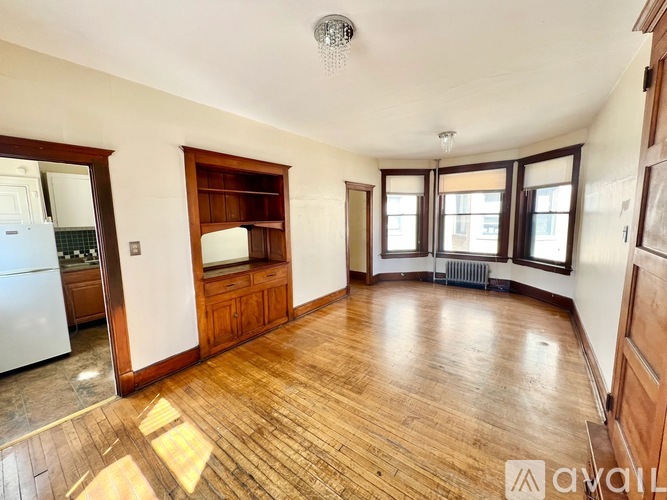 A spacious room with wooden floors and a large window.