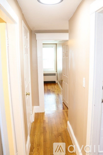 A hallway with wood floors and white walls.