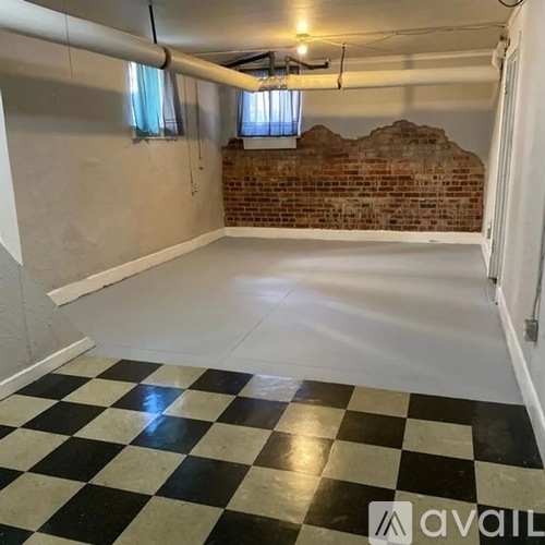 A room with a black and white checkered floor and a brick wall.