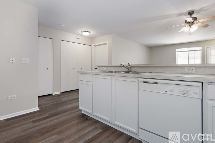 A kitchen with white cabinets and a wooden floor.