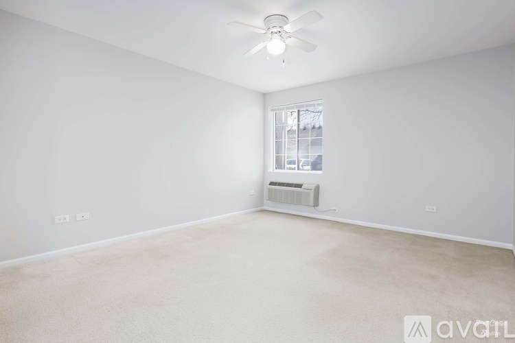 A room with a ceiling fan and a window with a view of a building outside.