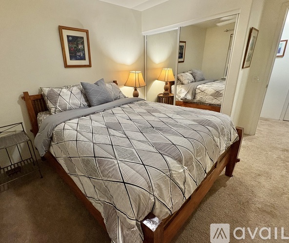 A bedroom with a large bed and two lamps.