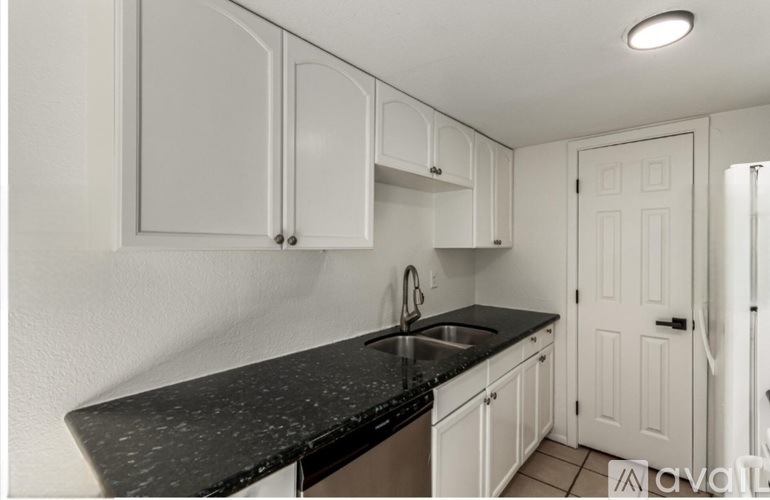 A kitchen with white cabinets and a black countertop.