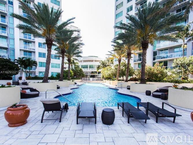 A pool surrounded by palm trees and lounge chairs.