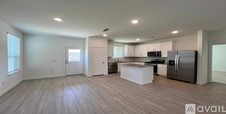 A spacious kitchen and living room with wooden flooring and modern appliances.