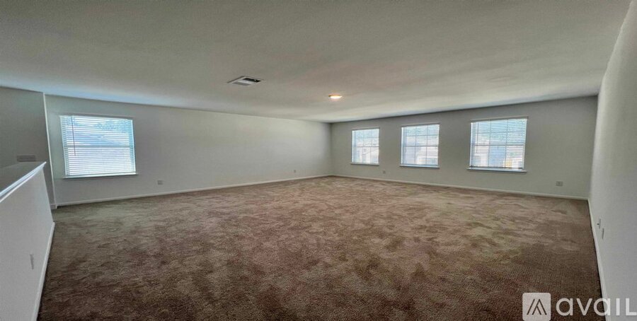 A spacious room with carpeted floor and large windows.