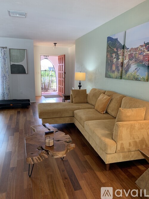 A living room with a tan couch and a wooden floor.