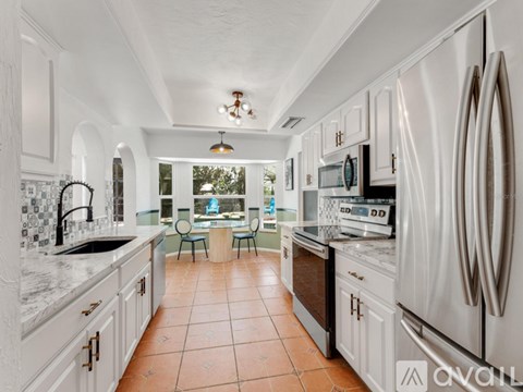 A kitchen with white cabinets and a tile floor.