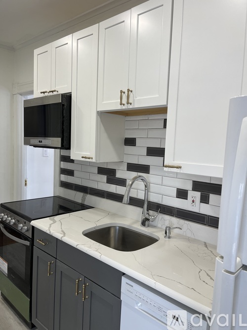 A kitchen with white cabinets and a black and white tiled backsplash.