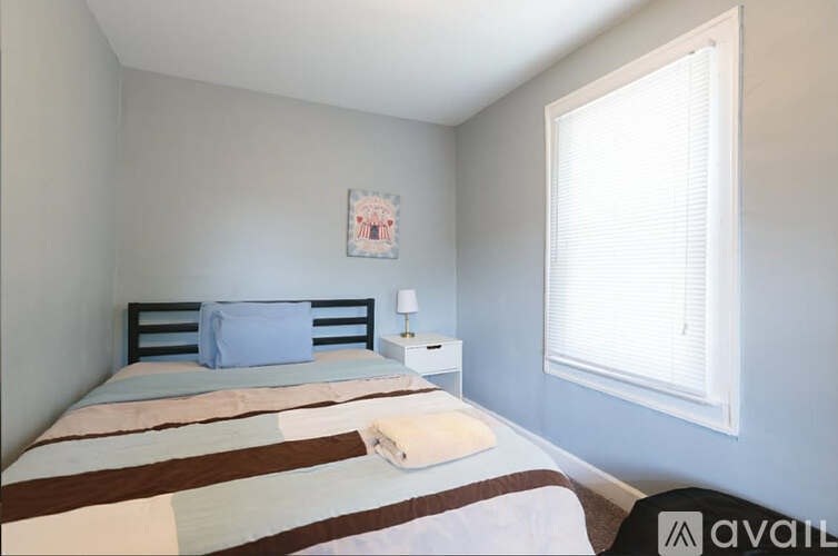 A bedroom with a bed, nightstand, and window.