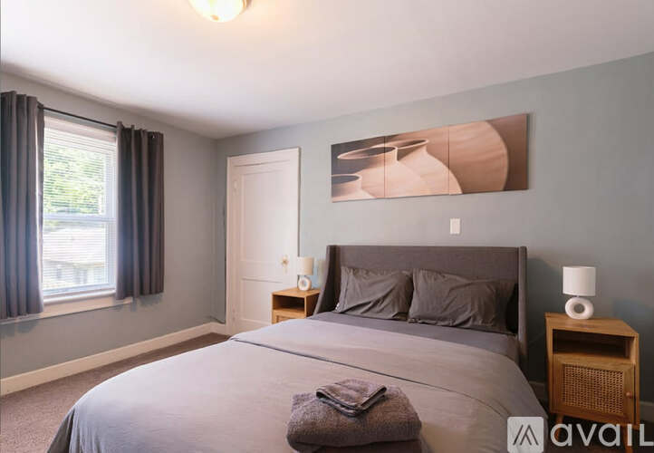 A bedroom with a large bed and a painting on the wall.