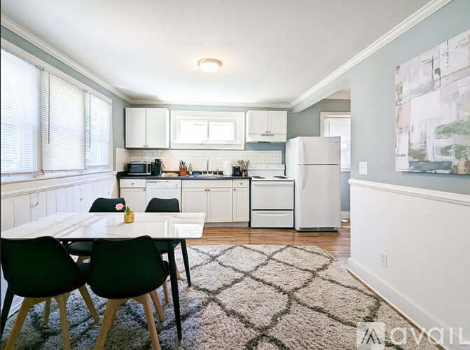 A kitchen with white appliances and a dining table with four chairs.
