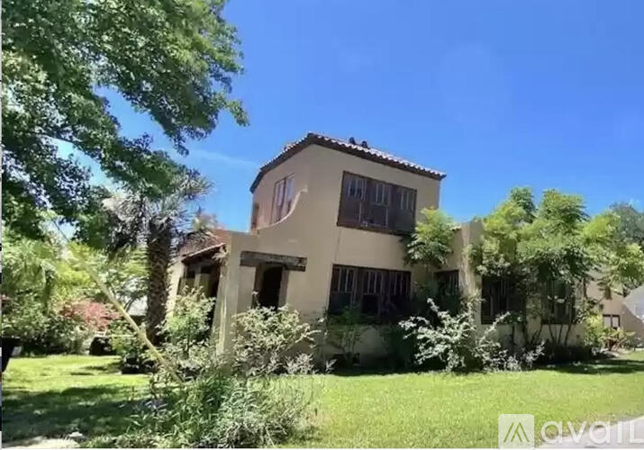 A house with a flag on the front is surrounded by greenery.