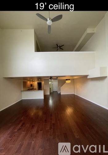 A room with a 19 feet ceiling and wooden flooring.