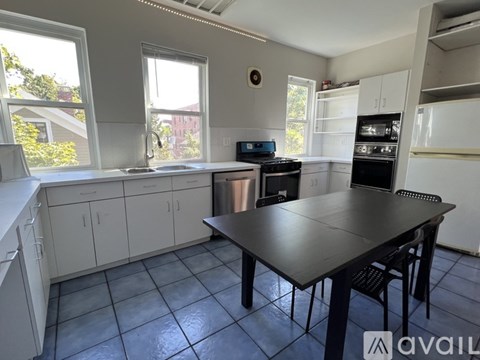 A kitchen with a table and chairs in the foreground and a window with a view of a building in the background.