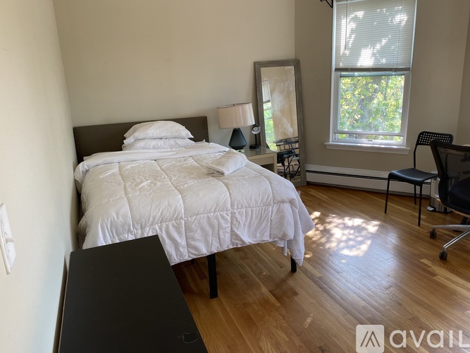 A bedroom with a large bed and a chair by the window.