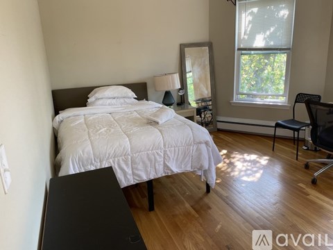 A bedroom with a large bed and a chair by the window.