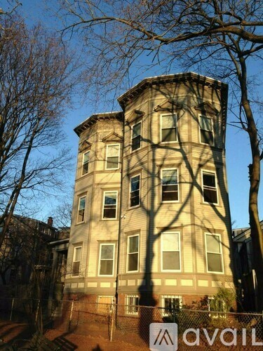 A tall building with many windows is surrounded by trees.