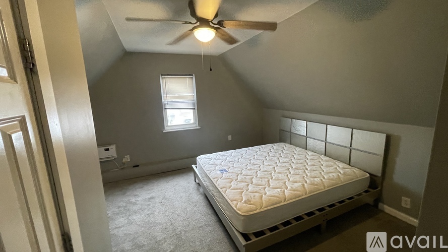 A bedroom with a bed, ceiling fan, and window.