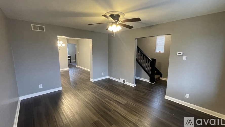 A spacious room with wood flooring and a ceiling fan.