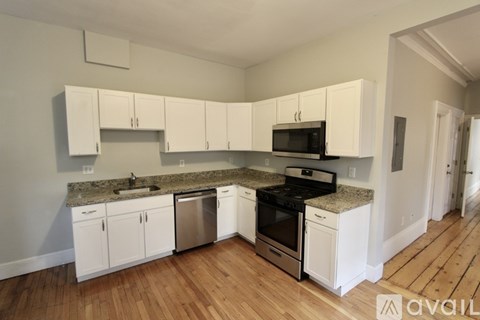 A kitchen with white cabinets and a granite countertop.