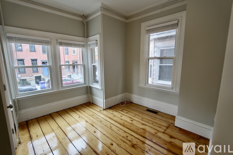 A room with wooden floors and two windows.