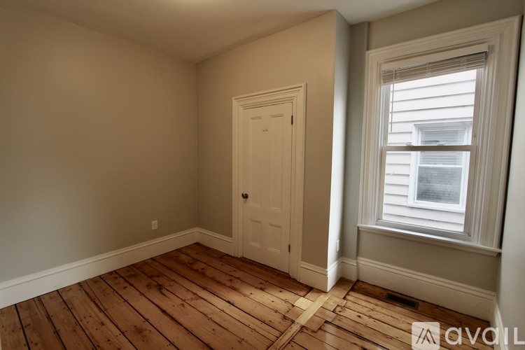 A room with wooden flooring and a window with blinds.